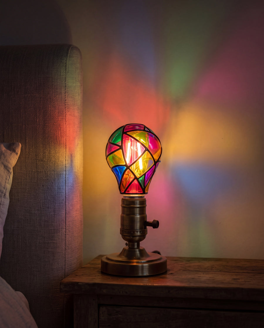 Mosaic Glow Bulb switched on in a brass bedside lamp